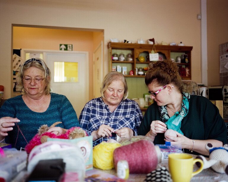 Three women knit together at a community hub in Torbay.