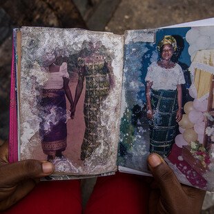 A young girl holds a family album damaged by floodwater