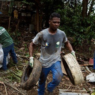 Four men collecting waste and old appliances from a ravine to eliminate mosquito breeding sites