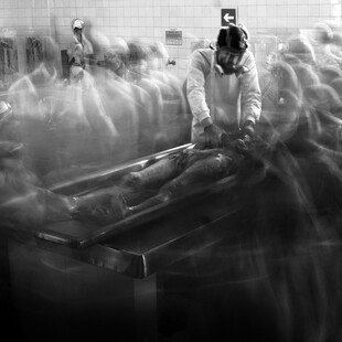 Worker in a morgue, surrounded by ghostly figures