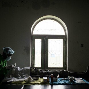 Using only natural light from a window, a trachoma surgeon operates on the eyes of a 13-year-old patient