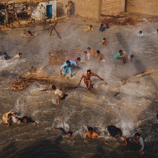People in a flooded Pakistani village scramble for food rations as they battle the downwash from an army helicopter delivering aid