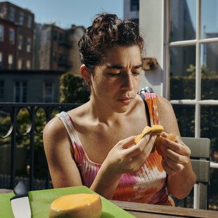 A woman cutting and eating a mango outside on a terrace