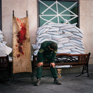 A man weeps beside a bloodied stretcher outside a medical centre.