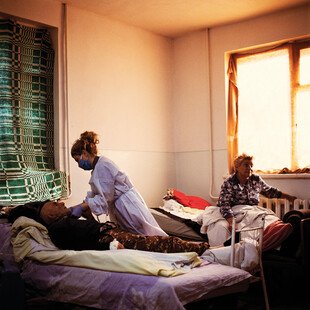 A nurse practitioner tends to a Covid patient in a hospital room. 