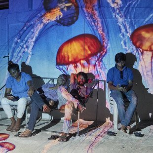 An underwater image is projected behind a group of men.
