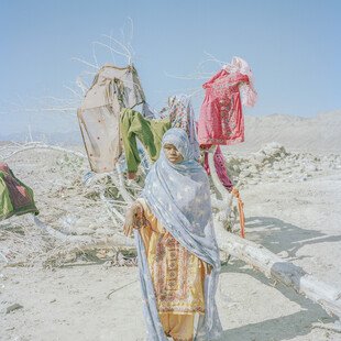 A young woman uses a dead tree for drying clothes. 