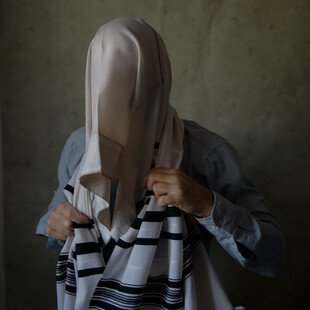 A man poses wrapped in his tallit prayer shawl to symbolise the way he conceals his identity from his religious community in Israel.